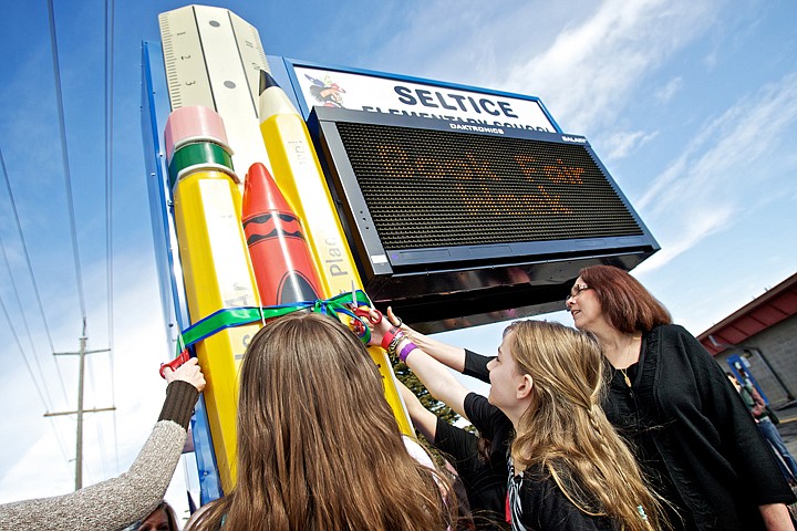 &lt;p&gt;JEROME A. POLLOS/Press Alannah Drake, 10, and Deidre Abbott, the PTO secretary, help cut a ribbon wrapped around the base of the new reader board for Seltice Elementary in Post Falls.&lt;/p&gt;