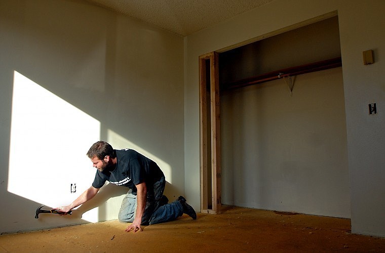 Allen Farmer uses a hammer to get at nails along the floor while remodeling an apartment complex on Hawthorn Avenue in Kalispell on Friday afternoon.