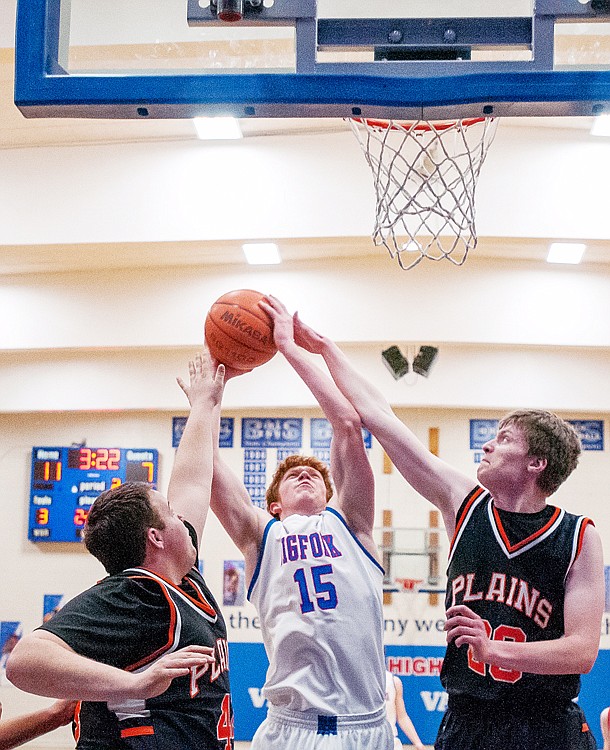 <p>Bigfork junior wing Josh Sandry (15) goes up for a shot while being fouled by Plains junior post Aaron Baker (right) Thursday night during a District 7B tournament semifinal game in Bigfork. </p>