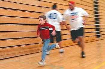 Brett Thompson, 7, speeds past Ed Mulitalo of the Detroit Lions in the 20-yard dash during the Winter Classic at Whitefish High School on Friday evening. The benefit event continues today with a picnic at the Whitefish Mountain Resort on the Northwest side of the Gray Wolf Run from 11 a.m. to 2 p.m. Nate Chute/Daily Inter Lake