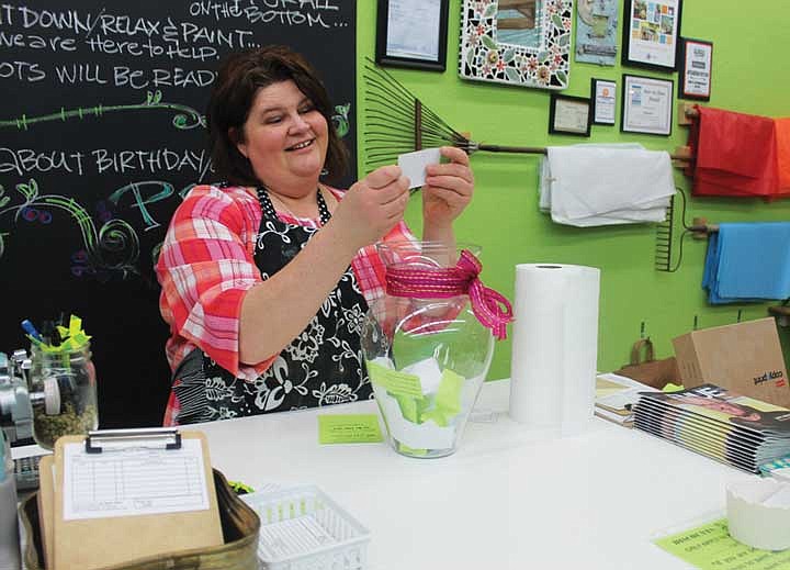 Artgarden Pottery owner Laura Mayer draws the winning raffle ticket during Friday night's &quot;Paint 'til You Faint&quot; event.