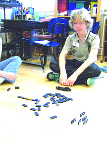 Miles Vaillancourt plays dominoes at a station last Wednesday. Students rotated around four different stations each tying themselves to a train aspect.