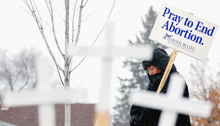 Dawn McMaster stands outside All Families Healthcare on North Meridian Road as a light snow falls Tuesday afternoon. McMaster said she stands vigil for one to two hours at least twice a week as part of the 40 Days for Life campaign.