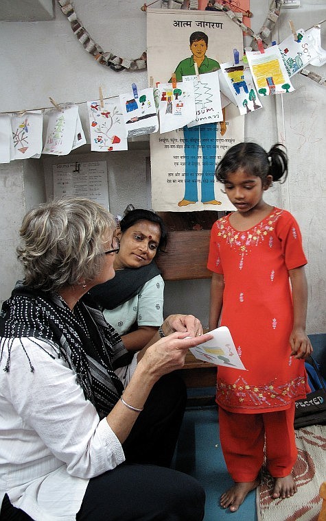 Regnier teaches beginning English to a student at a small school on the edge of Kidderpore as an Indian teacher looks on, helping with translation.