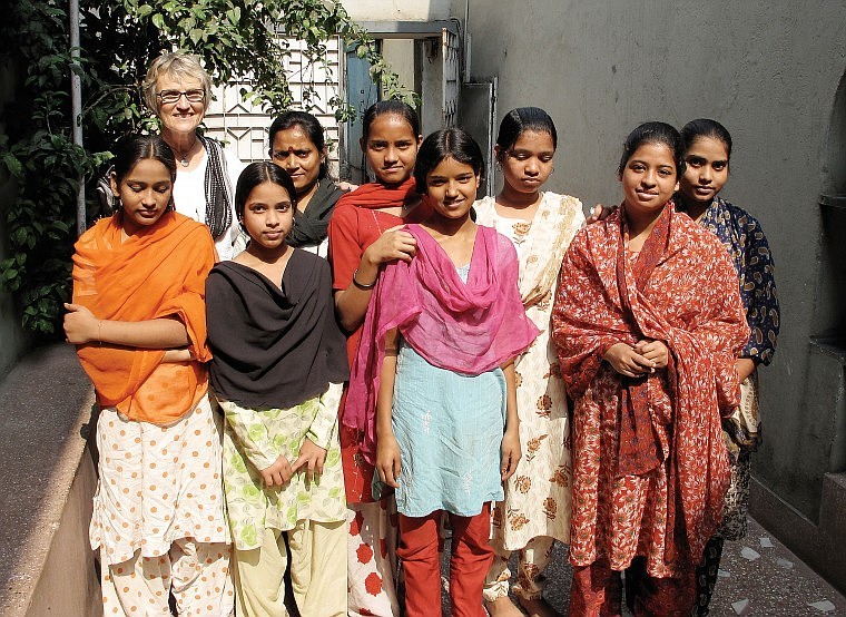 Regnier stands with a group of young students from the Kidderpore school. While Regnier teaches them English, the girls also learn computer and sewing skills at the center.