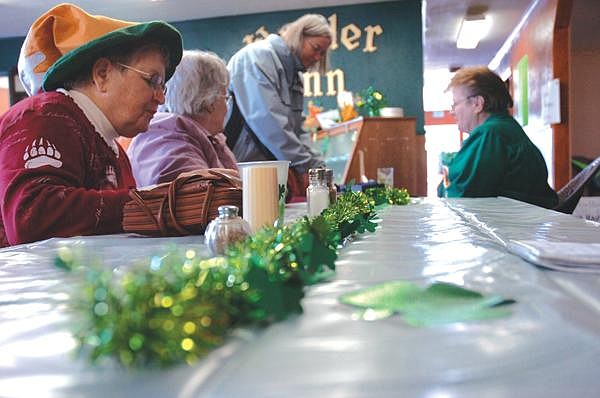 Edwina Aker, far left, eats an Irish dish while talking to friends at the Wander Inn, located inside the Heritage of Faith Church, Friday.