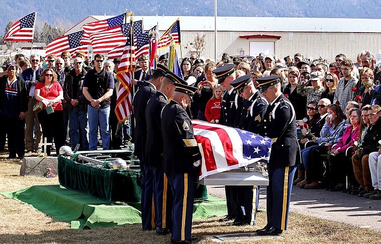 An honor guard of Montana National Guard carry the body of Army Pfc. Nicholas Cook as a crowd of community members and family look on at Woodlawn Cemetery in Columbia Falls Saturday afternoon.