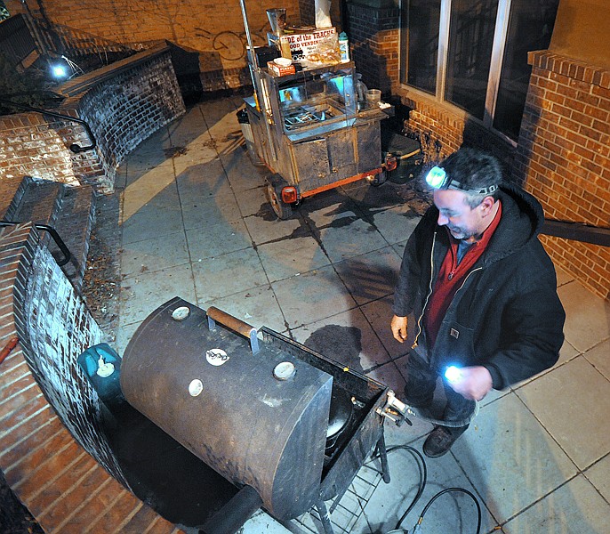 Michael Tigue of Columbia Falls working on the grill early on Saturday morning in downtown Whitefish. Tigue operates Side of the Tracks Food Vending, LLC., which offers pulled pork sandwiches, hot dogs, bratwursts, pretzels and chili. Saturday was his first night in Whitefish.
Adhering to the vendor law still on the books, the council last week approved a 60-day permit for a hot-dog and pulled-pork sandwich stand operated by Michael Tigue. His mobile stand is at 100 Central Ave.
Tigue said he, too, saw a vendor business as a way to help make a living right now. A stone mason whose job crumbled in the recession, Tigue got into cooking through barbecue competitions. He doesn&Otilde;t want any part of the controversy, though.