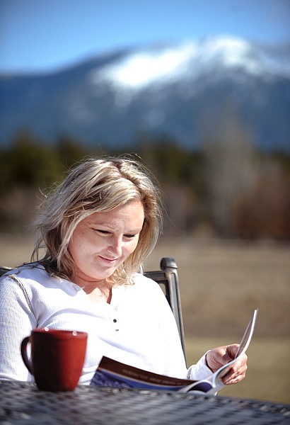 Tracie Rush of Columbia Falls takes a moment to enjoy a cup of coffee, a bowl of Cheetos and a copy of Montana Living out in the sunshine on Wednesday off Columbia Falls Stage Road.