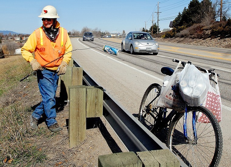 Richard Meidlinger, 76, uses a fishing pole with wiring attached to pick up an empty beer can along U.S. 93 in Kalispell Wednesday morning. Meidlinger says he usually picks up enough cans to fill up one to three plastic bags, often along local highways. &#147;Anything to get some exercise; it's just something to do,&#148; Meidlinger said.