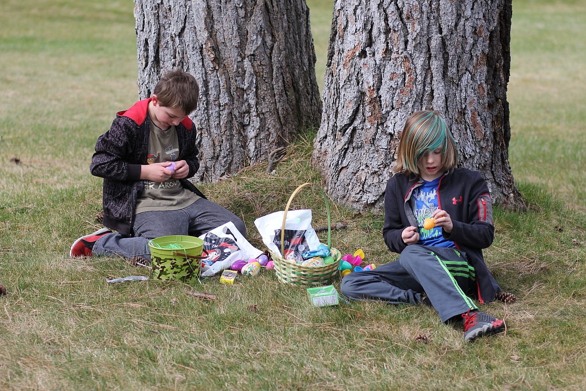 <p>Superior kids sit under a tree after their Easter egg hunt on Saturday and check out their prizes</p>