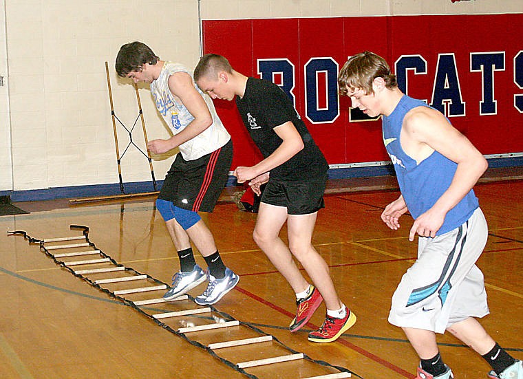 <p>Wyatt Zylawy, Nathan Lapinski and Bridger Lapierre jump between holes in a rope ladder during warm ups before a practice session for Superior's track and field team.</p>