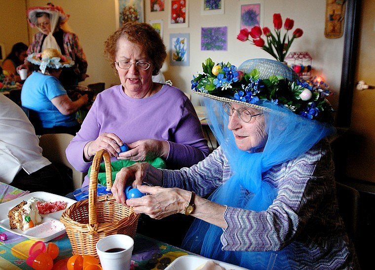 Alma Foot (blue hat) opens up Easter eggs with Janet Patterson during an Easter party Thursday afternoon at the Elms Apartments in Kalispell. Candy and quarters to help residents pay for laundry were hidden in the eggs.