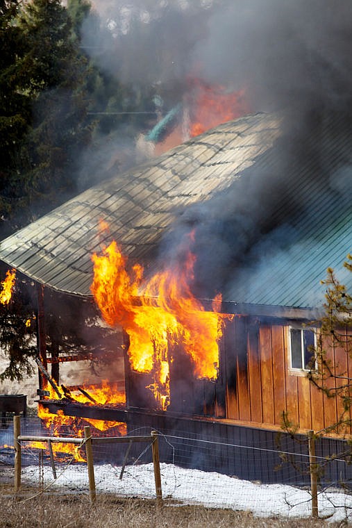 <p>Flames and smoke erupt from the roof of a home Friday morning on Truman Creek Road near Kila . April 4, 2014 in Kila, Montana. (Patrick Cote/Daily Inter Lake)</p>