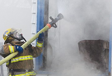 &lt;p&gt;A firefighter aims water into a house on 6th Street in Polson on Tuesday.&lt;/p&gt;