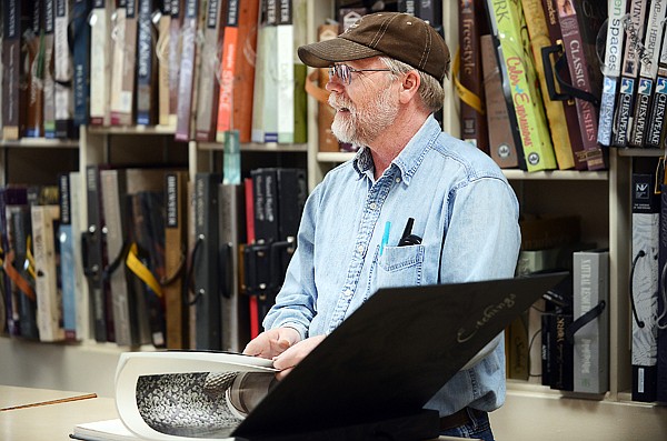 <p><strong>Dale Saverud </strong>helps a client look for a wallpaper pattern at Saverud Paint Shop on Wednesday in Kalispell. </p>