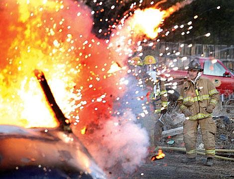 Photo by Ed Moreth Instructor Craig Jeppson takes a team of Plains firefighters to a burning car as the vehicle&#146;s air bag unexpectedly explodes. The team consisted of Prentiss Campbell, Sam Felix and Jon Knoepke. A dozen firefighters from the Town of Plains Volunteer Fire Department participated in a training operation at Valley Towing&#146;s wrecking yard.