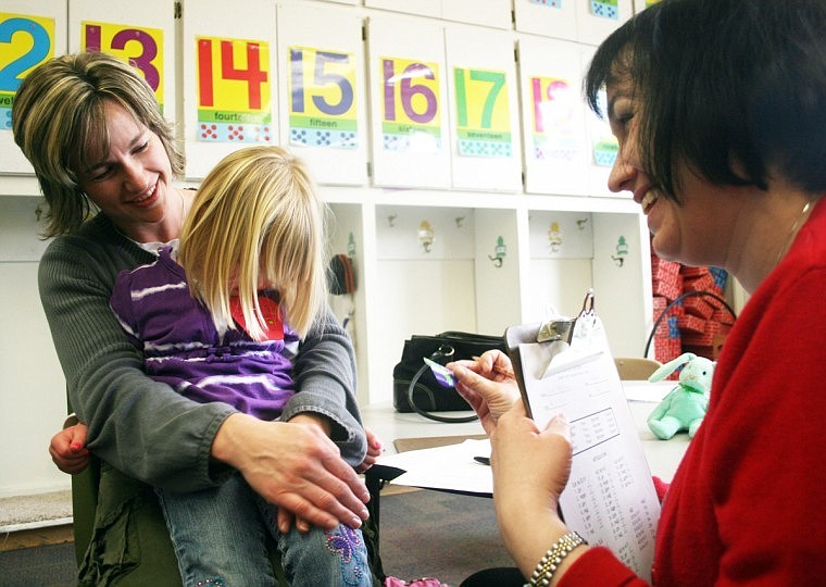 Lisa Burnham, a speech therapist, (left) gives Piper Bergstrom a sticker after her speech test. Her mother Kim sat in on the test.