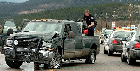 Kalispell Police officer Chad Zimmerman looks through the back of Scott Foster&#146;s Ford truck after Foster collided with a stopped tractor-trailer on U.S. 93 south of Kalispell Monday evening. Foster led police on a 20-mile high-speed chase around Kalispell and Somers before spike strips finally led Scott to lose control of the vehicle.Karen Nichols/Daily Inter Lake