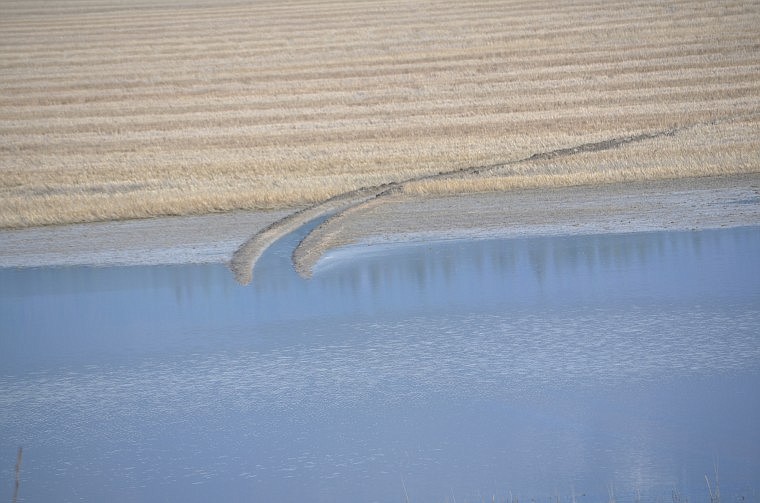 &lt;p&gt;A flooded area in a farm field shows tracks where someone tried to drive through it.&lt;/p&gt;