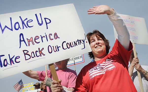 Dianna Soderholm of Marion waves to the vehicles passing by the Tax Day tea party at Depot Park in Kalispell on Thursday afternoon.