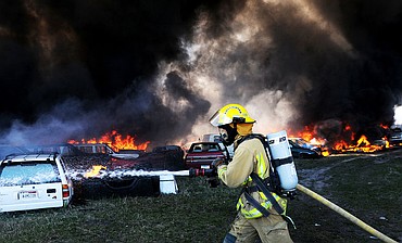 <p>South Kalispell Fire Department's firefighter Colter Effertz uses a hose to contain the fire at the A-1 Salvage near Somers on Friday. (Aaric Bryan/Daily Inter Lake)</p>