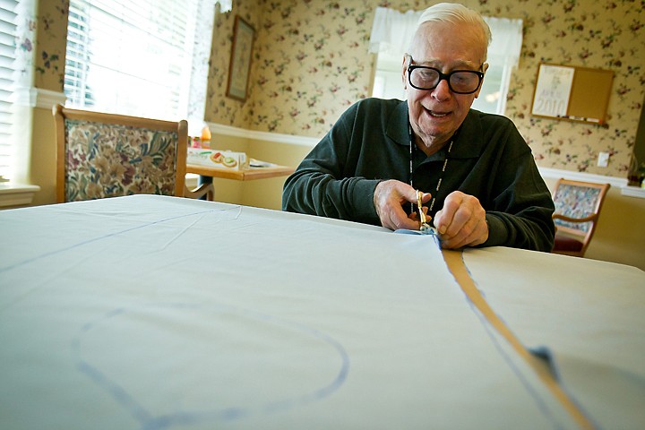 &lt;p&gt;JEROME A. POLLOS/Press Jim Williams cuts fabric to make clothing covers Wednesday at the Four Seasons Assisted Living Community in Coeur d'Alene. Residents, staff and other volunteers in the community are crafting 100 of the items to donate to various local care facilities and KMC.&lt;/p&gt;