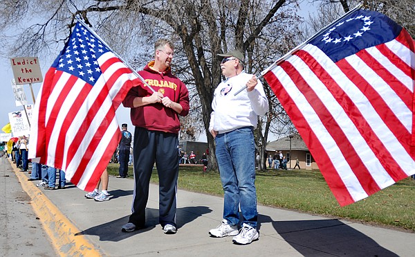 Michael Wise and Terry Faris, both of Kalispell, hold flags and wave to passing motorists at the Tax Day tea party on Thursday. Faris carries a flag with 13 stars that he bought in Spokane. &quot;I think we need to get back to basics with our government,&quot; said Faris. &quot;We seem to have forgotten the constitution.&quot;
