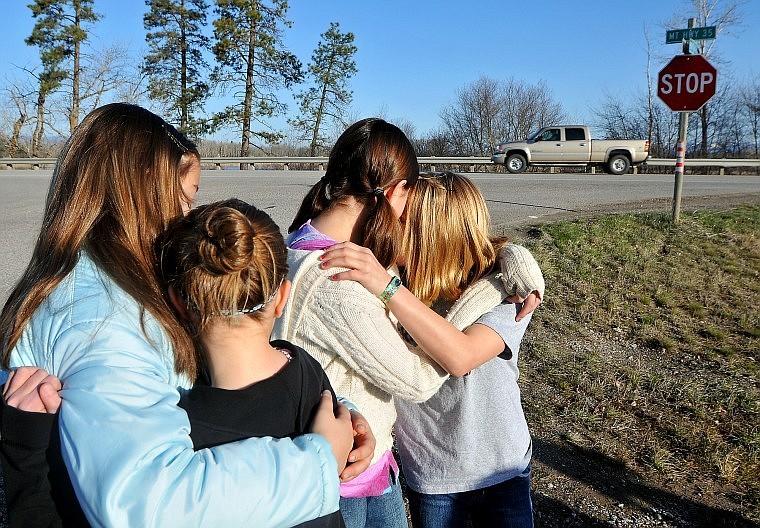 From left, Ashlee Burton, Madison Catlett, Hailey Gauthier and Shay Fournier embrace Friday morning near the intersection of Montana 35 and Montford Road following a memorial service remembering Hanna Cini, who died at age 6 in a traffic accident one year ago. The girls attended school with Cini at Fair-Mont-Egan School.