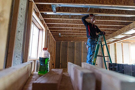 &lt;p&gt;Nickolas Akre, electrician apprentice for Super D Electrical, marks a 2x4 during construction on a Monogram Home Friday in Post Falls. The city is proposing a revision of its impact fees on new growth and the Planning and Zoning Commission will hold a public hearing on the topic on May 12.&lt;/p&gt;