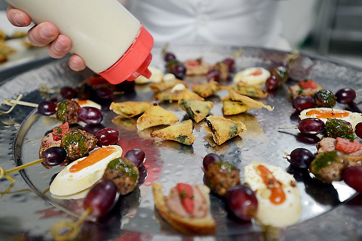 <p>Culinary Arts student Alex Hanson adds a finishing touch to a tray of appetizers at the Flathead Valley Community College spring fundraiser "Casablanca the Dinner" on Saturday, April 12, in Kalispell. The Bites to Begin included: Grilled Kefta with Cilantro dressing and grapes, Spinach Rolls with Caper-Pine Nut sauce, Crostini with grated almonds, fresh cheese, and tomato jam, and Berbere-cured chiken liver mousse. (Brenda Ahearn/Daily Inter Lake)</p>