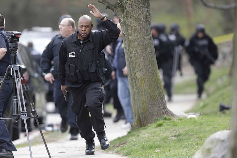 &lt;p&gt;A police officer signals for people to get back as they conduct a search for a suspect in the Boston Marathon bombings on Friday in Watertown, Mass. Two suspects in the bombing killed an MIT police officer, injured a transit officer in a firefight and threw explosive devices at police during a getaway attempt in a long night of violence that left one of them dead and another still at large Friday.&#160;&lt;/p&gt;