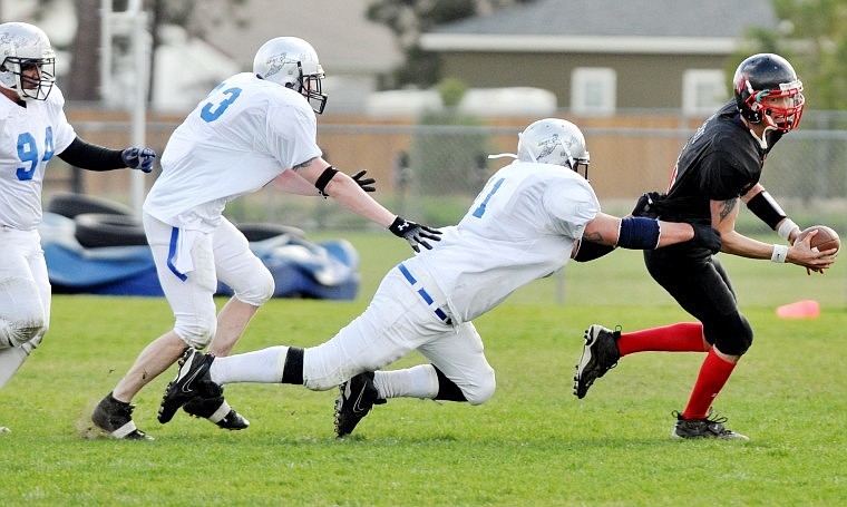 Glacier Knights Quarterback Phil Heimerl attempts to escape from a trio of Gallatin Valley Snow Devils, from left to right, Jonathan Garcia, Patrick Rice, and Larry Warner during a Rocky Mountain Football League game at Columbia Falls High School Saturday afternoon. The Knights won the game 15-0.