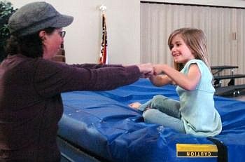 LEAP coordinator Cathy Gaiser bumps fists with Heather Wallace, 7, after she completed a flip off a small trampoline on Wednesday afternoon. Nate Chute/Daily Inter Lake