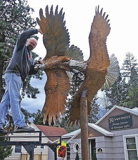 MIGRATING EAGLES - Libby school teacher and artist Todd Berget mounts his latest eagle sculpture -a pair of entangled bald eagles - on a pole in front of the Rivermist store. The steel and stainless steel sculpture is making a temporary stop at the California Avenue shop. It's destined for a buyer in Post Falls, Idaho.