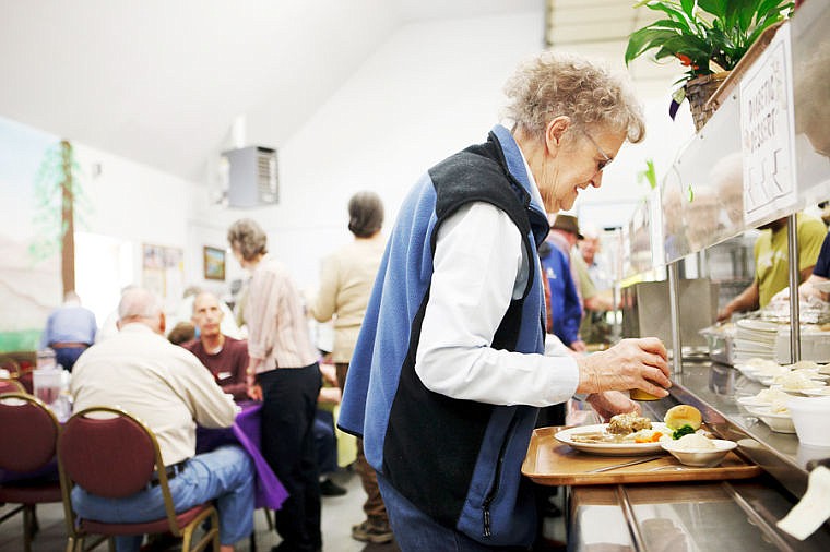 <p>Jane Seward grabs a glass of milk to go with her meal Friday afternoon during the congregate meals program at the Flathead County Agency on Aging facility on Kelly Road in Kalispell, Montana.</p>
<p> </p>