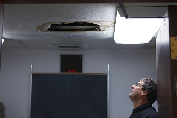 <p>Flathead High School principal Peter Fusaro looks at a hole in the ceiling of a coach's office during a recent tour of the school.</p>