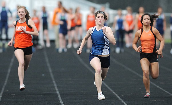 Glacier senior Maddey Frey (center) sprints to the finish line in the 100 in the crosstown dual with Flathead at Legends Stadium on Tuesday.