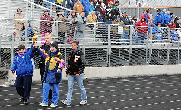 Matthew Bell and Becky West of the Krushing Boundaries team bring in the torch at the start of the Special Olympics on Friday in Kalispell.