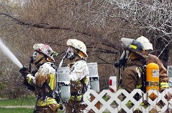 Firefighters spray water onto a garage after dousing it with foam on Tuesday. Nate Chute/Daily Inter Lake