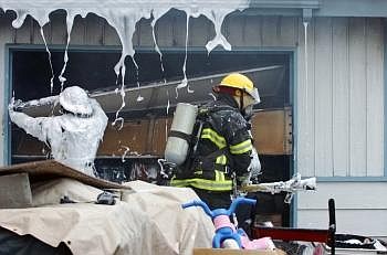 Area firefighters remove various items from inside a resident's garage after dousing the building with foam. Nate Chute/Daily Inter Lake