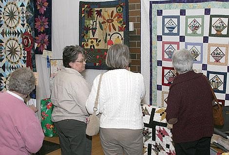 Photo by Adam Herrenbruck Visitors of the Flat Iron Quilting Guild&#146;s 2008 Quilt Show admire the work of Donna Abrams, the featured quilter at the show in Thompson Falls. Abrams&#146; quilt &#147;Arrowhead Crossing&#148; won the Critic&#146;s Choice at the show, which ran Friday through Sunday in the Thompson Falls High School gym.