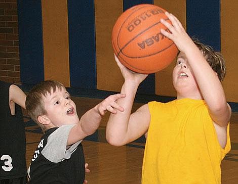 Photo by Adam Herrenbruck Wade Wood of the yellow team goes up for a shot as Kyle Willhite of the black team attempts to defend him at the Thompson Falls High School gym. Last Tuesday, the Little Dribbler program (grades three and four) held the final two games of their 14-game season with yellow beating black and blue beating red.