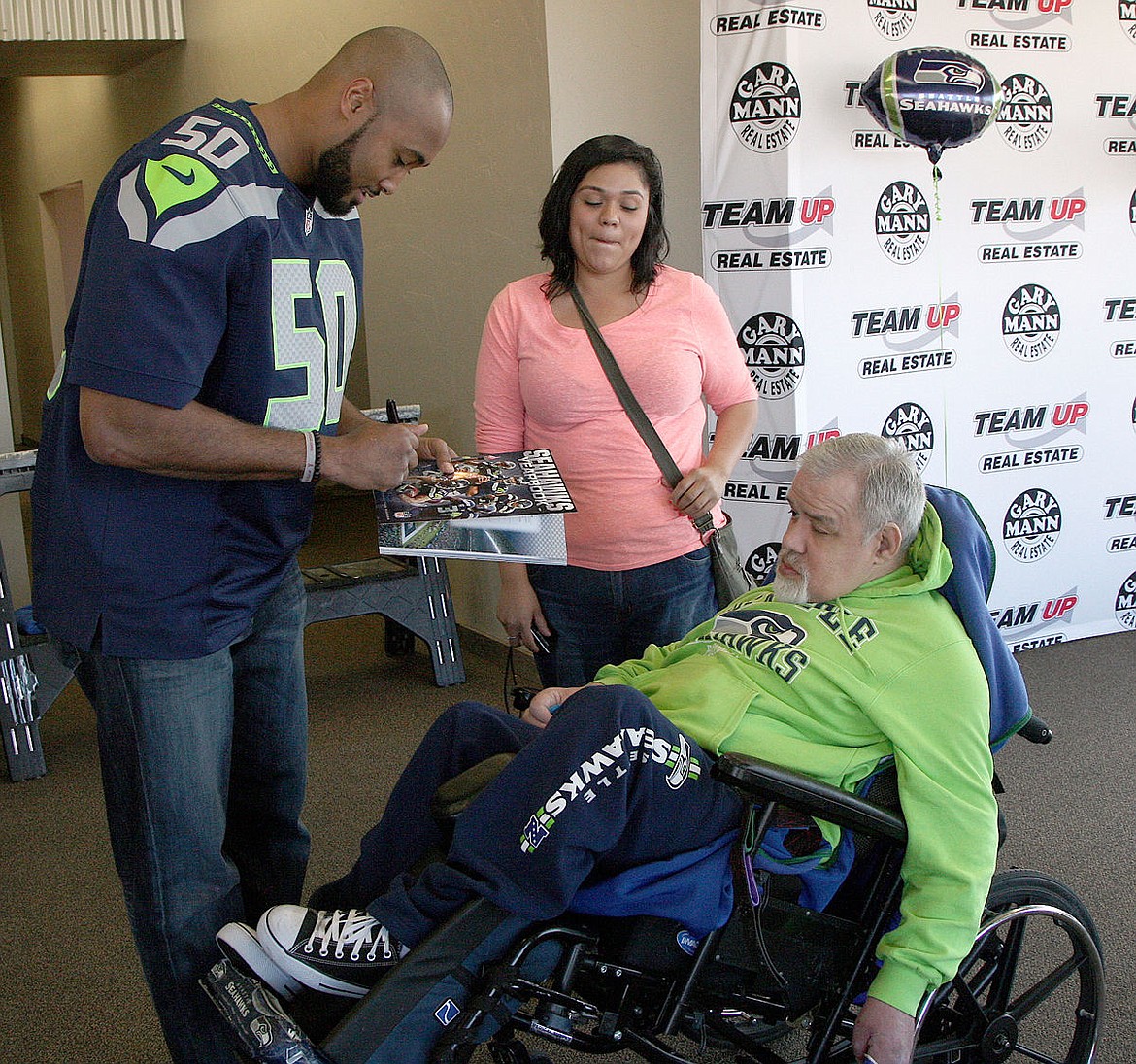 Seattle Seahawks linebacker K.J. Wright signs an autograph for Sal Valdez of Moses Lake Saturday. Wright was in Moses Lake to help raise money for the Moses Lake Medical Team.