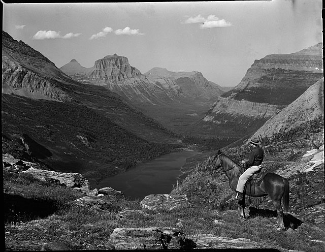 Horses have long been used in Glacier Park and most trails are cut to accomodate them. Here, assistant Chief Ranger Dick Nelson and steed red Eagle, 1947. This view looks back toward Mt. Siyeh and Citadel.