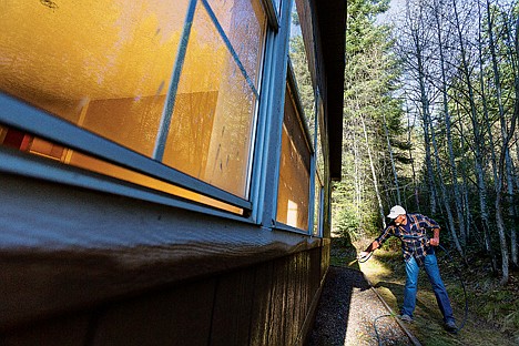 &lt;p&gt;Chris Hammons uses a sprayer to paint the largest cabin at his Hauser Lake property.&lt;/p&gt;