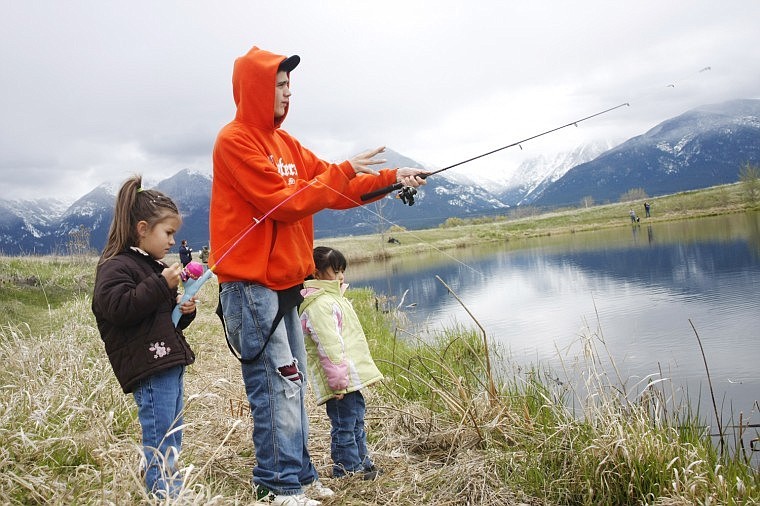 Arnold Cardenas, of Arlee, teaches his daughter Alizia Huff (right) and her friend Kaitlyn Miller how to fish on Saturday during the Kids Fishing Day Tournament at Ninepipes Pond.