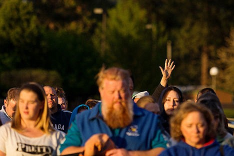 &lt;p&gt;An attendee of the candlelight vigil raises their hand in praise among a group of hundreds.&lt;/p&gt;