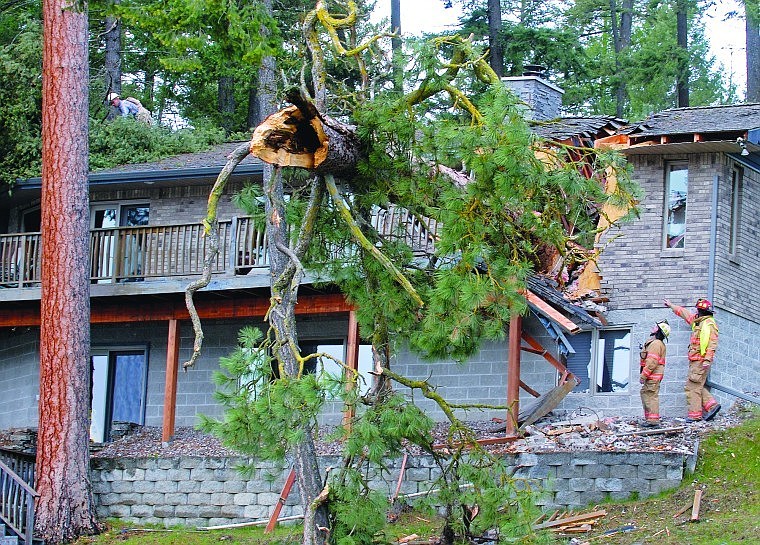 Two Bigfork firefighters inspect damage done to the home of Andrew and Rosemary Kovatch near Echo Lake Monday afternoon when a tree was blown over in a windstorm. Peak wind gusts from Monday&#146;s storm ranged from 41 mph at Glacier Park International Airport to 93 mph at Logan Pass in Glacier Park. Monday&#146;s wind is expected to give way to snow today in the Flathead Valley. The National Weather Service predicts 1 to 4 inches of snow today with a high temperature of 42.