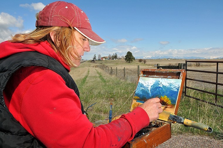 Under much-clearer skies Friday than Flathead residents have seen for a few days, Kelly Apgar paints a landscape scene just off of U.S. 93 near Somers.